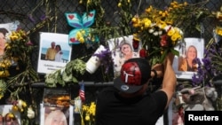 A man places flowers on a makeshift memorial for the victims of the Surfside's Champlain Towers South condominium collapse in Miami, Florida, July 8, 2021. 