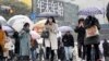 Para pejalan kaki berjalan melintasi persimpangan Shibuya di Tokyo, saat salju turun, Kamis, 6 Januari 2022. (AP Photo/Kiichiro Sato) 