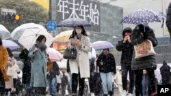 Para pejalan kaki berjalan melintasi persimpangan Shibuya di Tokyo, saat salju turun, Kamis, 6 Januari 2022. (AP Photo/Kiichiro Sato) 