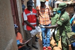 Member of the country's armed forces and a Red Cross worker distribute food to people affected by the lockdown measures aimed at curbing the spread of the new coronavirus, in the Bwaise suburb of the capital Kampala, Uganda, April 4, 2020.