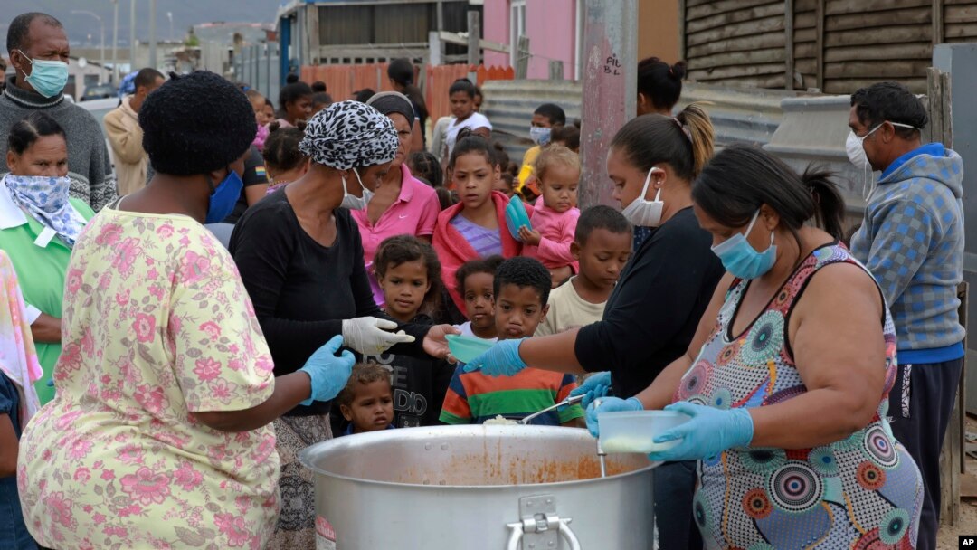 Anak-anak antre untuk mendapatkan jatah makan mereka di Lavender Hill, Cape Town Afrika Selatan, Selasa, 21 April 2020, pada minggu keempat karantina dalam upaya mengatasi penyebaran virus corona. (Foto AP / Nardus Engelbrecht)