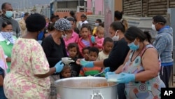 Anak-anak antre untuk mendapatkan jatah makan mereka di Lavender Hill, Cape Town Afrika Selatan, Selasa, 21 April 2020, pada minggu keempat karantina dalam upaya mengatasi penyebaran virus corona. (Foto AP / Nardus Engelbrecht)