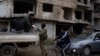 A member of the new armed forces, a former rebel who took part in the overthrow of Bashar Assad's government, checks the ID of a person at a checkpoint in the district of Khalidiya, Homs, Syria, Jan. 1, 2025.