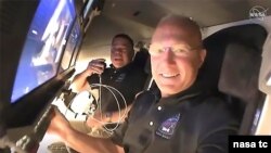 NASA astronauts Doug Hurley (foreground) and Bob Behnken call down to mission controllers for a report on their second flight day aboard the SpaceX Crew Dragon. (Credit: NASA TV)
