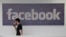 FILE - Facebook employee walks past a sign at company headquarters in Menlo Park, California.