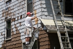 A worker for Viking Painting coats the exterior of a house, June 5, 2020, in Euclid, Ohio. U.S. unemployment dropped unexpectedly in May to 13.3% as reopened businesses began recalling millions of workers faster than economists had predicted.