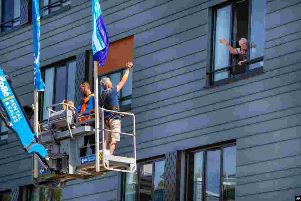 Pitrik van der Lubbe waves from a crane to his 88-year-old father Henk, right, at a nursing home in Gouda, Netherlands. The crane was made available for free by a company to allow family members to see loved ones in isolation because of the coronavirus.