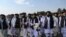 Juru bicara Taliban Zabihullah Mujahid (tengah, membawa selendang) didampingi oleh para pejabat untuk membrikan keterangan kepada media di bandara Kabul, 31 Agustus 2021. (WAKIL KOHSAR / AFP)