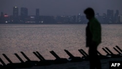 A visitor walks along on a beach equipped with anti-landing barricades, with the Chinese city of Xiamen seen in the background, in the Taiwan-controlled Kinmen islands, in Kinmen on May 17, 2024.