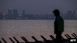 นักท่องเที่ยวเดินเล่นที่ชายหาดเกาะจินเหมินที่เต็มไปด้วยขวากป้องกันการยกพลขึ้นบก โดยอีกฝั่งของทะเล คือเมืองเซี่ยเหมินที่ห่างออกไปเพียง 5 กม. วันที่ 17 พฤษภาคม 2024 (ที่มา: AFP)