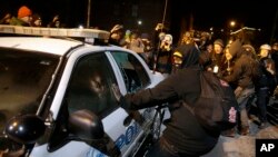 Demonstran merusak mobil polisi dekat Balai Kota Ferguson di Missouri (25/11). (AP/David Goldman)