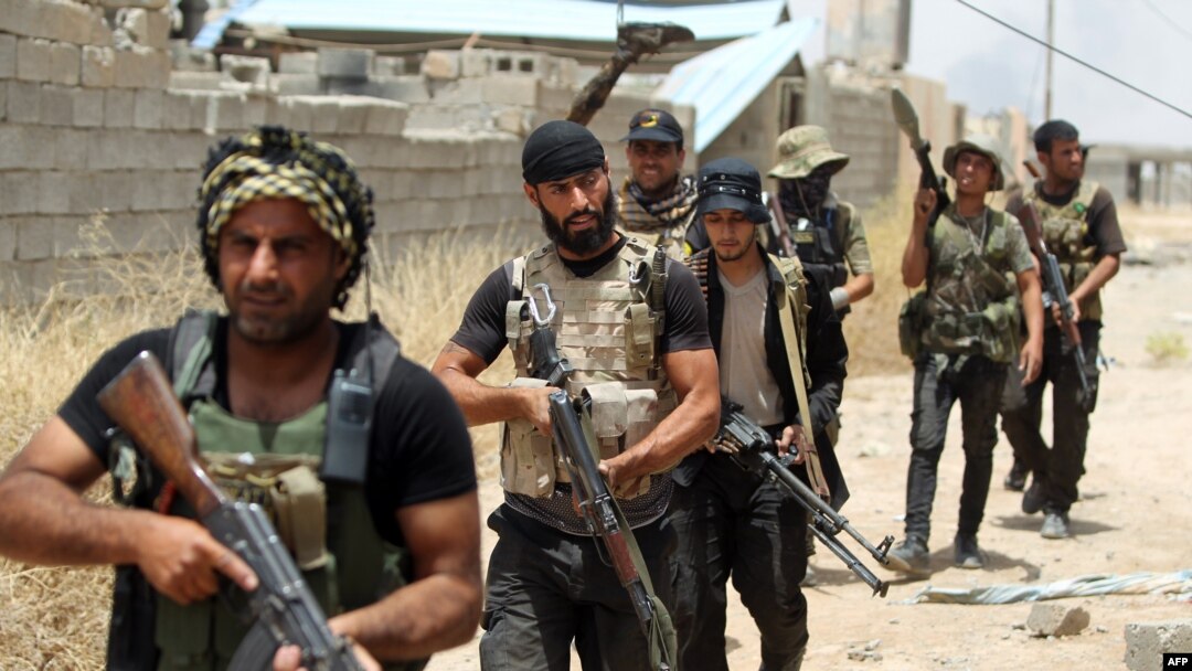 FILE - Fighters from the Popular Mobilization units deploy in the city of Baiji, north of Tikrit, as they fight alongside Iraqi forces against the Islamic State, June 9, 2015. 