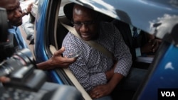 Surrounded by journalists, pastor Evan Mawarire is seen in a vehicle after being freed on bail in Harare, Zimbabwe, Feb. 9, 2017. (S. Mhofu/VOA)