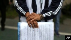 A handcuffed inmate holds a sheet of music in a prison courtyard in Callao, Peru, as he waits to be transported to a classical music session with a symphony orchestra in the national theater in the Peruvian capital, July 19, 2019.