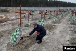 Masyarakat mengunjungi kuburan orang tak dikenal, pada hari peringatan pertama serangan Rusia di Ukraina, di Bucha. (Foto: Reuters)