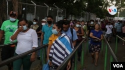 Trabajadores salen de una empresa privada en Managua, unos con máscaras, otros sin ellas. Foto VOA.