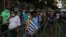 Trabajadores salen de una empresa privada en Managua, unos con máscaras, otros sin ellas. Foto VOA.