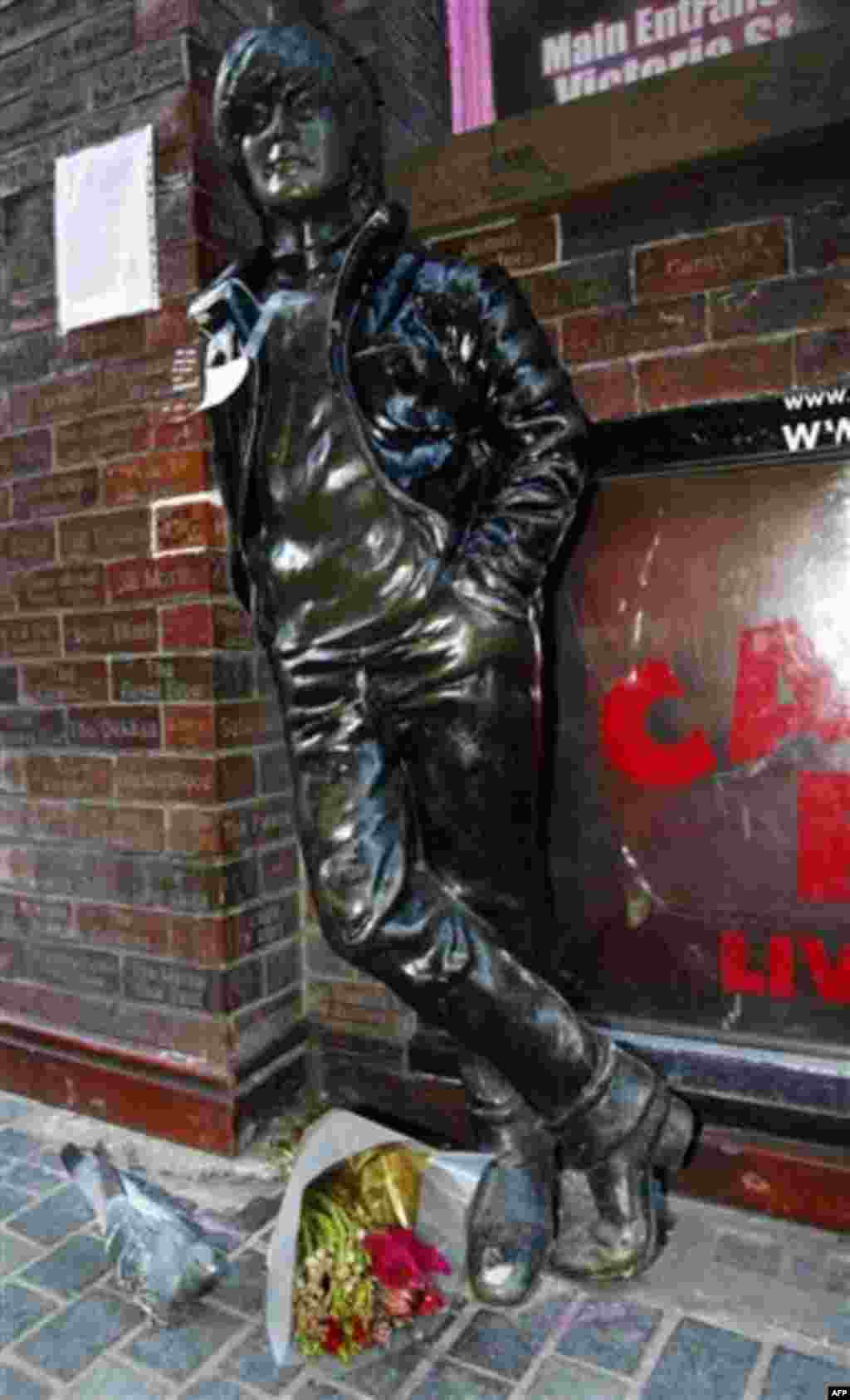 A note and flowers left at a statue of John Lennon outside the Cavern Pub in Mathew Street, Liverpool, England, Wednesday Dec. 8, 2010. Beatles fans will mark the 30th anniversary of John Lennon's death with a candlelit vigil at the city's European Peace 