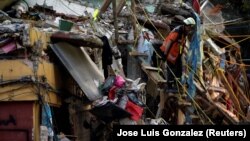 Seorang anggota tim penyelamat Argentina berjalan menuruni tangga dengan anjing pelacaknya, di lokasi perumahan multi-keluarga yang runtuh, setelah gempa bumi, di Mexico City, Meksiko 24 September 2017. (Foto: REUTERS/Jose Luis Gonzalez)