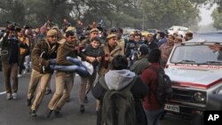 A protesting student is detained by a policemen outside Uttar Pradesh Bhawan during a protest against a new citizenship law and violence by police in the state, in New Delhi, India, Dec. 27, 2019. 