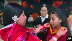 Mirian Masaquiza ayuda a su hija a vestirse mientras su esposo, Oscar, observa, mientras la pareja se unía a una boda masiva celebrada en el Lincoln Center de Nueva York, el sábado 8 de julio de 2023.