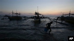 ငါးဖမ်းစက်လှေမှာ အသုံးပြုမယ့် သိုလှောင်ခန်းအသစ်တခု ရေချ သယ်ဆောင်လာနေတဲ့ ဖိလစ်ပိုင်လူငယ်တစ်ဦး။