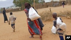 A newly-arrived Somali family carry their supply of aid outside Dadaab, Eastern Kenya, 100 kms (60 miles) from the Somali border, Aug. 5, 2011