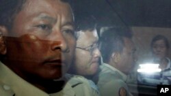 Ny Chakrya, second from left, former ADHOC and a National Election Committee member who worked at the organization, sits in a car and is transported back to an Anti-Corruption Unit, ACU, after a short appearance at Phnom Penh Municipal Court, in Phnom Penh, Cambodia, Saturday, April 30, 2016. 