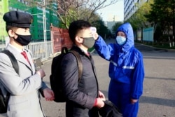 A student wearing a face mask has his temperature checked as a precaution against a new coronavirus as their university reopened following vacation, at Kim Chaek University of Technology in Pyongyang, April 22, 2020.