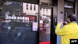 FILE - People pass the electoral office of Australian federal Labor Party member of parliament Josh Burns in the Melbourne suburb of St. Kilda after police said at least five people smashed windows and painted slogans on the walls on June 19, 2024.
