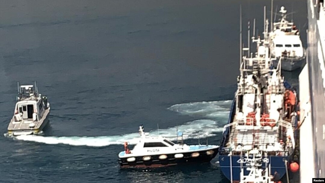 Para migran dipindahkan dari kapal milik LSM Aita Maria ke kapal Italia, Rubattino di lepas pantai Palermo, Italia, Minggu, 19 April 2020. Mereka dipindahkan untuk dikarantina karena wabah virus corona (Covid-19).