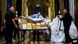 Organizers cover the boxed cremated remains of Mexicans who died from COVID-19 before a service at St. Patrick's Cathedral, Saturday, July 11, 2020, in New York. The ashes were blessed before they were repatriated to Mexico. (AP Photo/Eduardo Munoz…