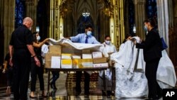 Para petugas menutup kotak-kotak berisi abu jenazah pasien yang meninggl akibat Covid-19, sebelum misa di Gereja Katedral St. Patrick, New York, 11 Juli 2020. (Foto: AP)