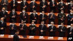 Los delegados que usan máscaras para ayudar a frenar la propagación del coronavirus aplauden cuando el presidente chino, Xi Jinping, llega a la sesión de apertura del Congreso en el Gran Salón del Pueblo, el 4 de marzo de 2021. 