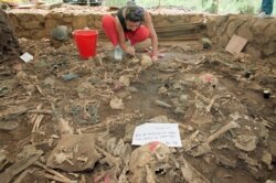 ARCHIVO - En esta fotografía del 23 de octubre de 1992, la antropóloga forense Claudia Bernard, de Argentina, limpia la tierra de los restos humanos en El Mozote, El Salvador.