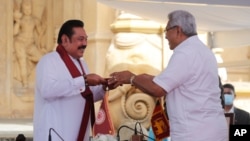 Sri Lanka’s former President Mahinda Rajapaksa, left, receives appointment documents from his younger brother, President Gotabaya Rajapaksa, after being sworn in as the prime minister at Kelaniya Royal Buddhist temple in Colombo, Sri Lanka, Aug. 9, 2020.