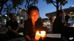 FILE - A woman lights candles during a service for peace on the Korean Peninsula near the U.S. Embassy in Seoul, South Korea, Aug. 31, 2017. 