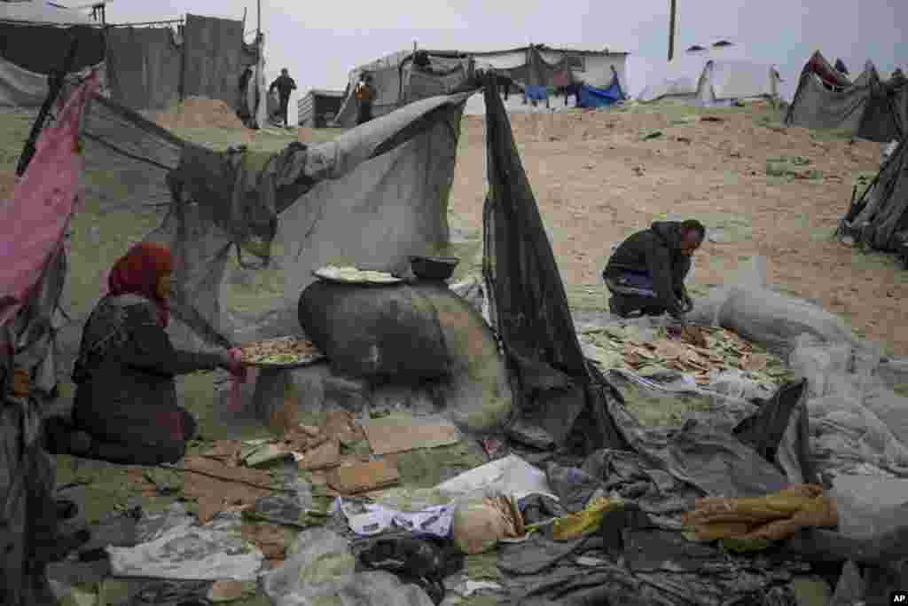 Mona Al-Zebda, displaced from Gaza City, bakes bread at a tent camp for displaced Palestinians at the Muwasi, Rafah, southern Gaza Strip.