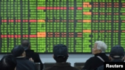 FILE - Investors sit in front of a board showing stock information at a brokerage house on the first day of trade in China since the Lunar New Year, in Hangzhou, Zhejiang province, China, Feb. 3, 2020. 