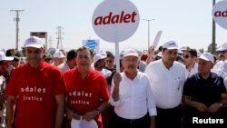 FILE - Turkey's main opposition Republican People's Party (CHP) leader Kemal Kilicdaroglu (C) and Secretay-General of the Socialist International Luis Ayala (2nd L) walk flanked by supporters during the 14th day of a protest dubbed "justice march" against the detention of CHP's lawmaker Enis Berberoglu, in Duzce, June 28, 2017. The placard reads "Justice."