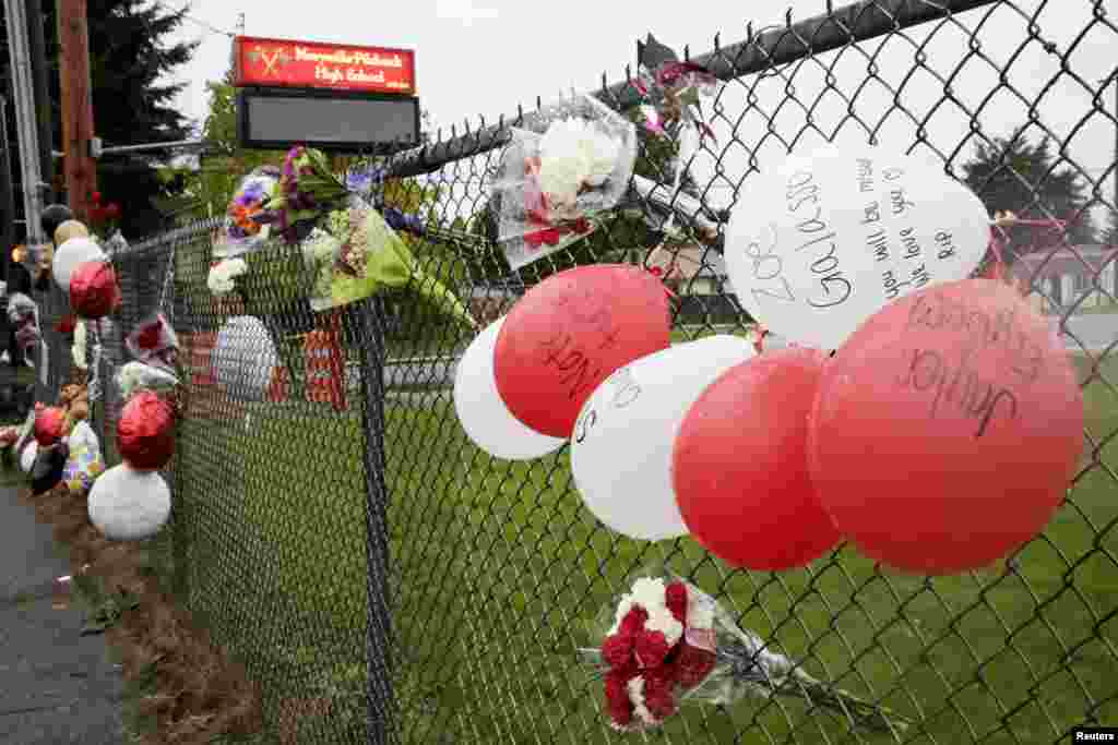 Balloons and flowers are tied to a fence outside of Marysville-Pilchuck High School as a memorial to the victims of a school shooting in Marysville, Washington, Oct. 25, 2014.