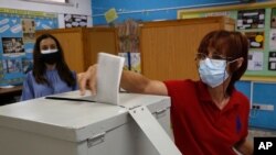 A woman wearing a protective mask casts her vote at a polling station during parliamentary elections, in Deftera, a suburb of capital Nicosia, Cyprus, May 30, 2021. 