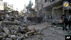 This photo provided by the Syrian Civil Defense White Helmets, which has been authenticated based on its contents and other AP reporting, shows citizens clearing debris in a street a day after airstrikes hit, in the Damascus suburb of Arbeen, Syria, July 25, 2017.