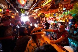 FILE - Patrons crowd into the tiny interior of the Tiki-Ti bar as it reopens on Sunset Boulevard in Los Angeles, July 7, 2021.
