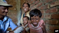 Foriza Begum, background, a newly arrived Rohingya Muslim from Myanmar, reacts to her daughter Nosmin Fatima's scream as she receives a vaccination to prevent measles and rubella at a makeshift medical center in Teknaf, Bangladesh, Oct. 2, 2017.