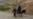 An Afghan man walks with a burqa-clad woman and children riding a donkey along a hillside in the Argo district of Afghanistan's Badakhshan province on October 12, 2026.