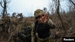 Ukrainian serviceman gestures next to a self-propelled howitzer before firing toward Russian troops on a front line in Zaporizhzhia region