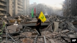 Un hombre lleva una bandera de Hezbolá mientras camina por los escombros de un edificio destruido por un ataque aéreo israelí en Dahiyeh, Beirut, en Líbano, el 1 de noviembre de 2024. (Foto AP/Hassan Ammar)