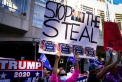 President Donald Trump supporters gather with some signs claiming a stolen election outside the Philadelphia Convention Center as they await general election tabulation results, Nov. 6, 2020, in Philadelphia.