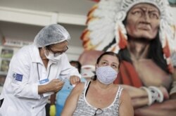 A woman receives a dose of Sinovac's CoronaVac coronavirus disease (COVID-19) vaccine at Cacique de Ramos, one of the most traditional carnival blocks of Rio de Janeiro, Brazil, April 8, 2021.